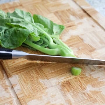 Chinese broccoli with trimmed, peeled stems and small vertical slits cut into the thick bases.