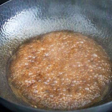 Simmering sauce in a pan over medium heat until it thickens