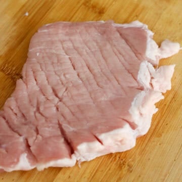 Cut slits along the fat (this prevents pork from curling as it fries). Tenderize pork with a meat mallet or with the back of your knife until about 1 cm thick.