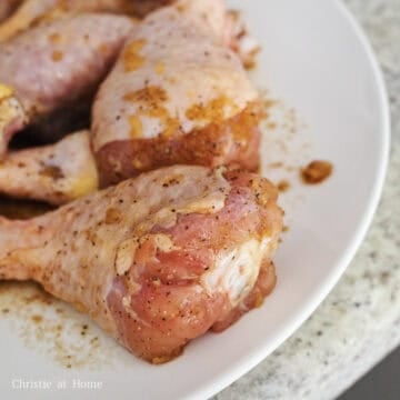 Raw chicken drumsticks coated in a soy sauce and garlic marinade.