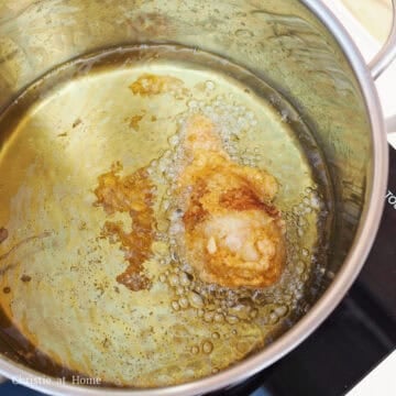 Battered chicken drumsticks frying in hot oil until golden brown and crispy.