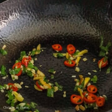 Minced garlic, ginger, red chilis, green onions, and sugar sizzling.