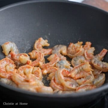 Pink shrimp par-cooked and lightly seared on the edges.
