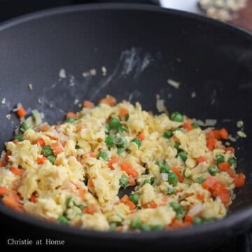 Scrambled yellow eggs broken into small pieces and tossed with colorful vegetables.