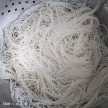 A bowl of softened rice vermicelli noodles being strained.