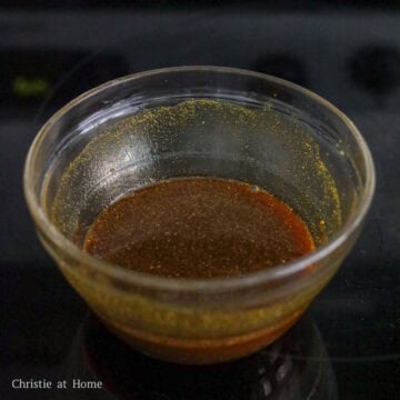 Dry yellow curry powder, soy sauce, and white sugar being whisked together in a small bowl.