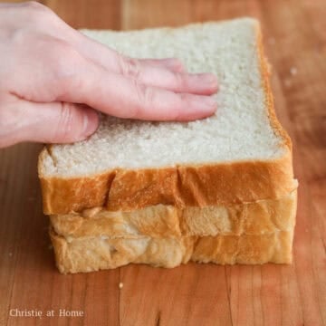 Three slices of white milk bread stacked with two layers of peanut butter filling.