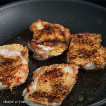 Searing chicken thighs skin-side down until golden