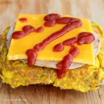 Next warm up the ham slices in the pan for 10 seconds on each side and place ham on top of omelette followed by cheddar cheese slices. Drizzle ketchup on top of the cheese.