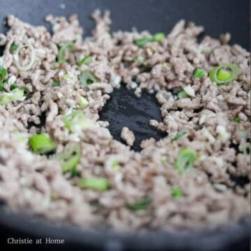 Heat vegetable oil in a large non-stick pan on medium heat and cook minced meat for about 4-5 minutes until liquids have evaporated. Then add minced garlic, ginger and scallion whites and stir fry with meat.