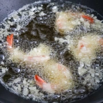 In a large heavy bottomed pan, heat vegetable oil or any neutral oil on medium high heat until you reach 350 degrees F with a digital instant read cooking thermometer. Or insert a wooden spoon into the hot oil and look for rapid bubbles. Lower battered shrimp into the hot oil away from you. Fry in small batches, about 3-4 pieces per batch.