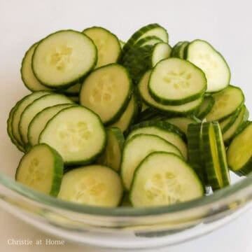 Sliced cucumbers inside a large mixing bowl.