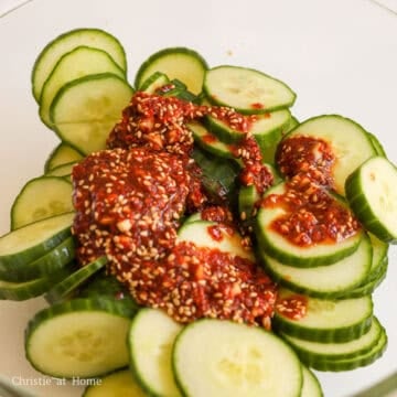 Red dressing poured over cucumber slices in a bowl.