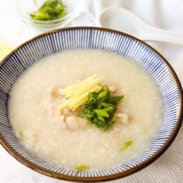 Creamy chicken congee garnished with scallion greens and fresh ginger.