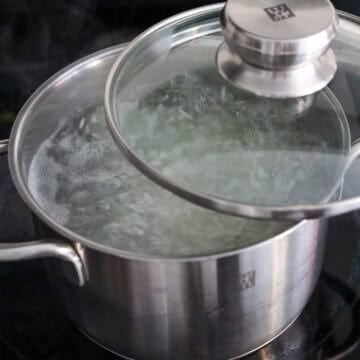 Jasmine rice simmering in water with the lid halfway open.