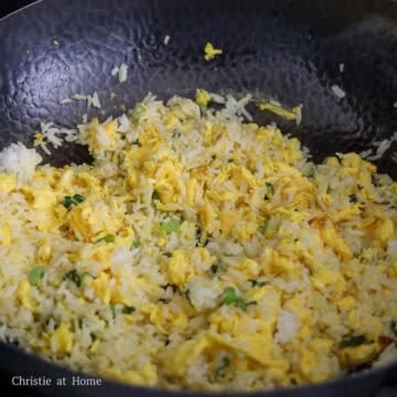 Green onions sautéing with egg fried rice in a wok