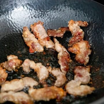 Pork shoulder pieces frying until golden brown and crisp on both sides.
