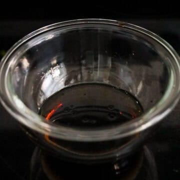 Soy sauce, sesame oil, rice vinegar, and sugar being whisked together in a bowl.