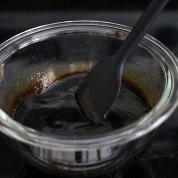 Whisking the homemade hoisin noodle sauce ingredients together in a small glass bowl.