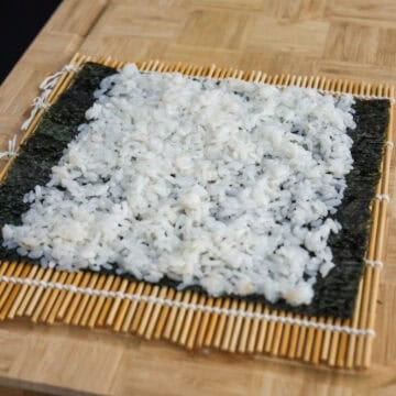 Lay out 1 sheet of gim or nori vertically with rough side up on a clean working surface. Evenly spread out ¾ cup of seasoned rice into a thin layer with gloved hands, clean wet fingers or with a wet rice paddle. Leave 1-inch borders at the end of the seaweed sheet.