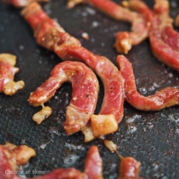 Marinated flank steak strips sizzling in a hot pan with vegetable oil.