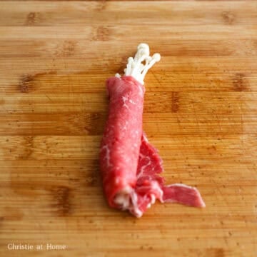 Enoki mushrooms tightly wrapped in thinly sliced beef with tops exposed.