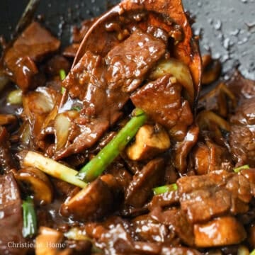Beef, mushrooms, onions, and green onions coated in glossy stir-fry sauce.