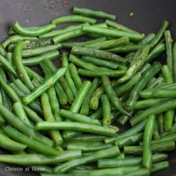 Add remaining vegetable oil into the pan followed by string beans and ⅓ cup or 80 ml of water. Toss for 10 seconds. Then cover and steam until all the water has evaporated and the string beans taste tender, about 3-4 minutes. If not tender yet, add 2 tablespoons or 30 ml of water and continue steaming until they are.