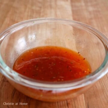 A vibrant sweet chili sauce, red sriracha, amber honey, clear rice vinegar, fresh lime juice, and green lime zest mixed together into a smooth, glossy red glaze.