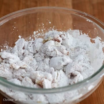 Cubed chicken thighs evenly coated in a fine, white dusting of cornstarch and dry spices with no bare spots.