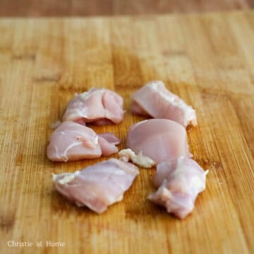 Raw skinless boneless chicken thighs cut into uniform 1.5 inch cubes piled together.
