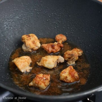 Bite-sized pieces of cornstarch-coated chicken frying in shimmering oil, turning a deep golden brown with a crispy exterior.